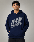 A man wearing a navy blue pullover hoodie with a bold white graphic reading 'NEW MLIMBA!' across the chest, posed against a neutral gray studio background.